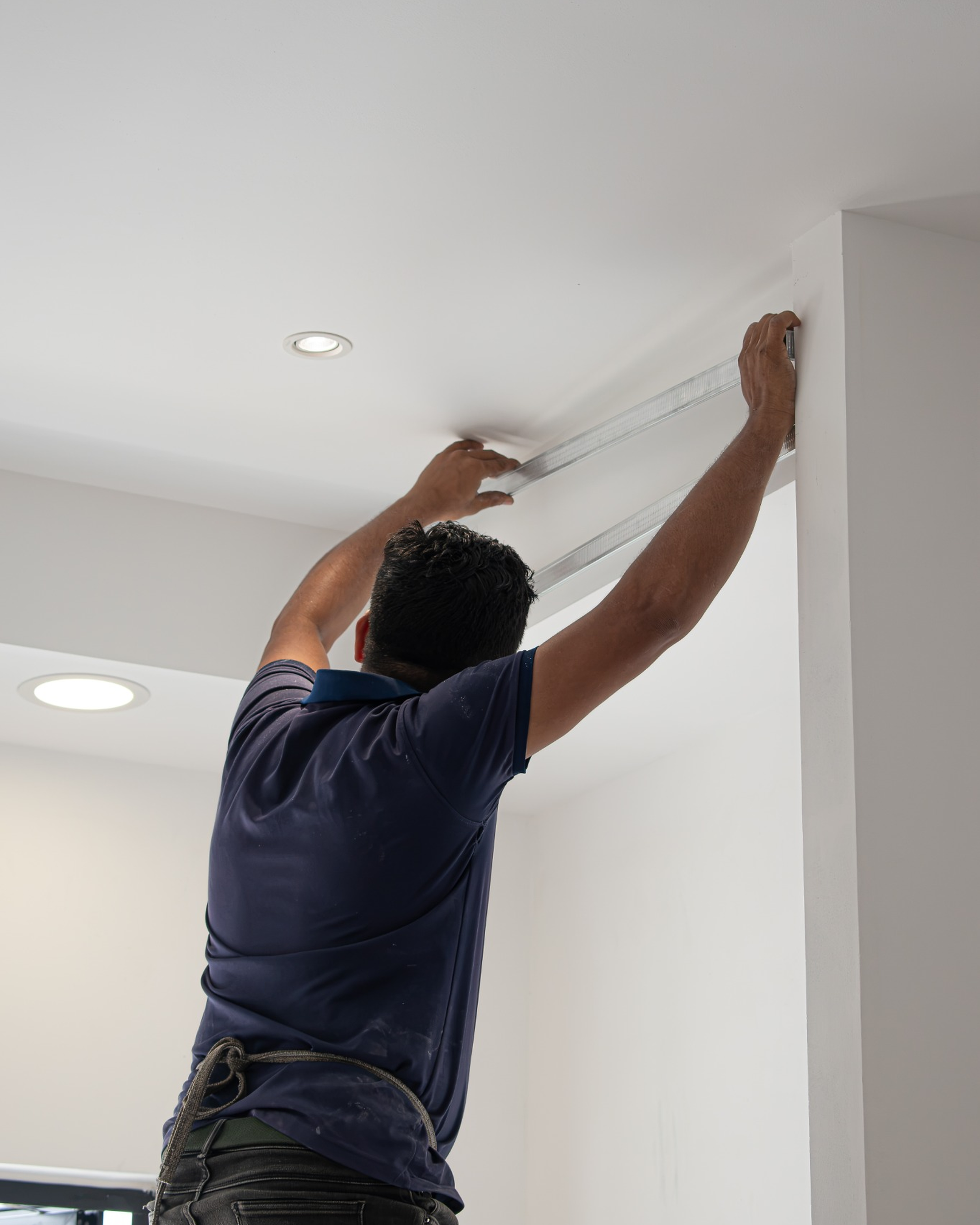 Worker measuring ceiling framing for renovation works