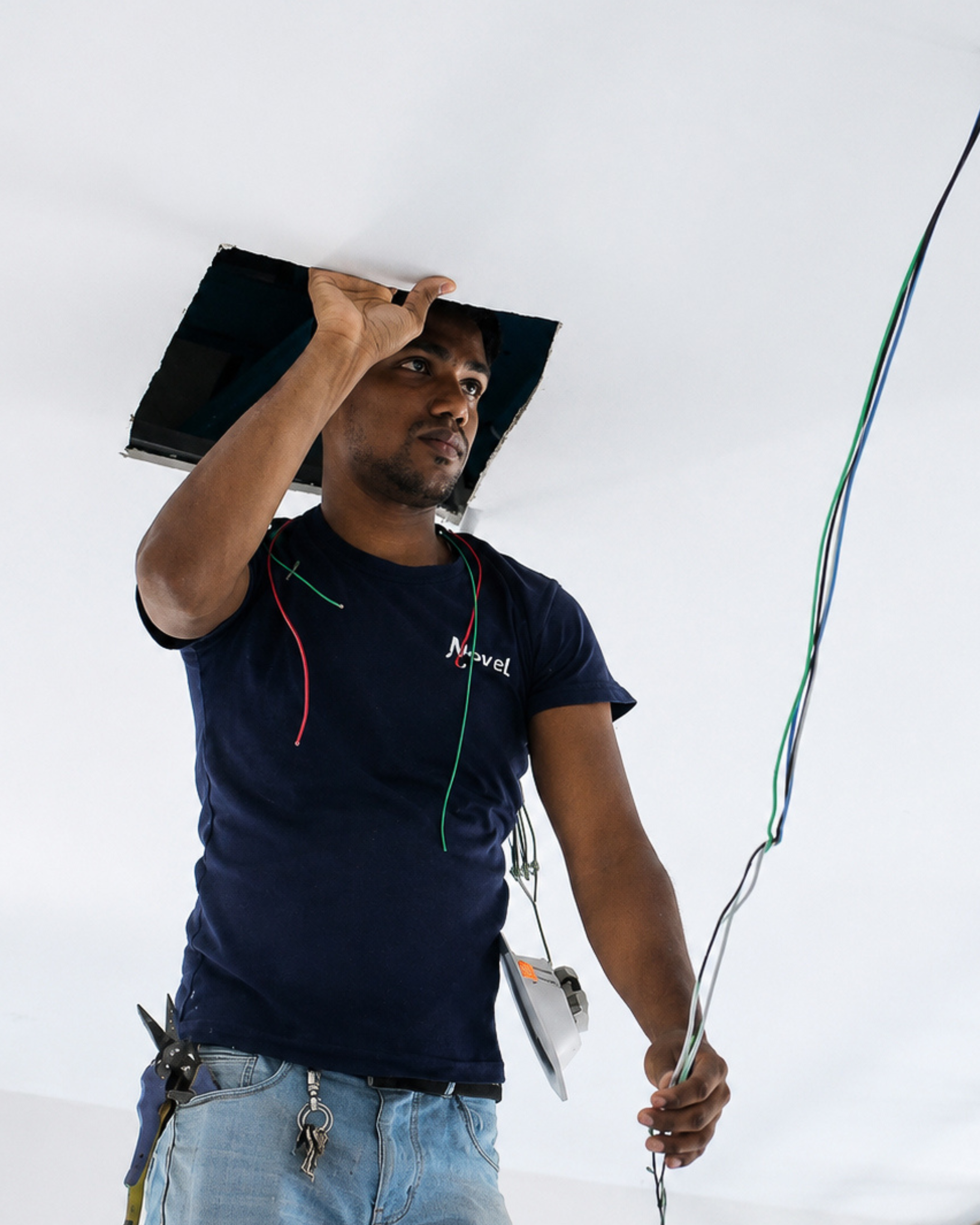 Electrician managing wiring through a ceiling opening